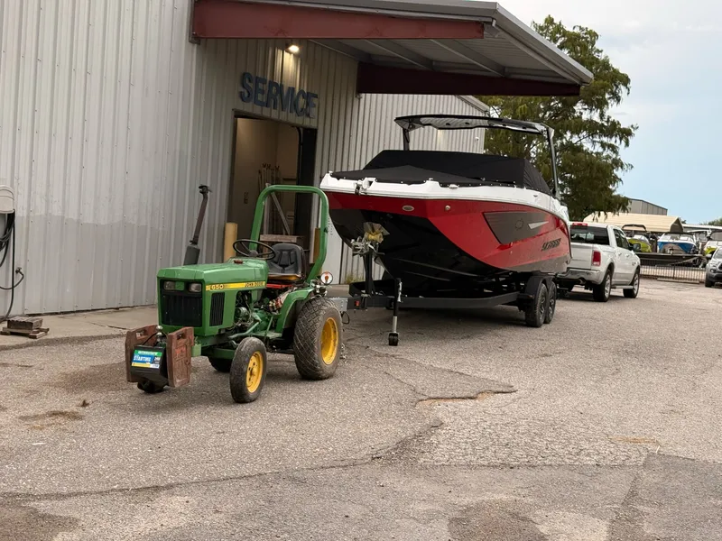 Slide: The Image of 2026 Scarab 285 LX boat outside a service shop with tractor. - 7