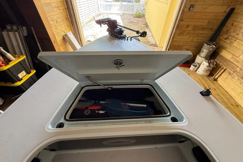Slide: The Image of Open storage compartment on 2025 Chittum Skiffs 18 Islamorada boat in a wooden garage. - 13
