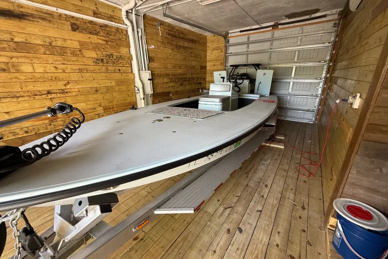 Slide: The Image of 2025 Chittum Skiffs 18 Islamorada boat in wooden garage, side view. - 17