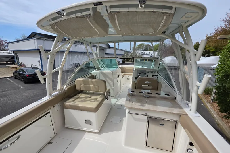 Slide: The Image of 2019 Sailfish 275 DC boat interior with seating and helm, docked outdoors. - 5