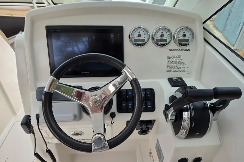 Slide: The Image of 2019 Sailfish 275 DC helm with steering wheel, Garmin display, and control gauges. - 8