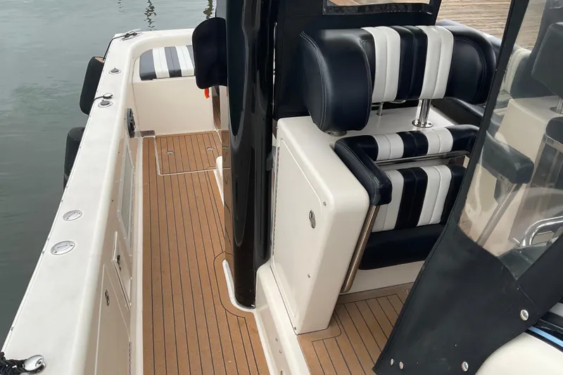 Slide: The Image of 2004 Rivolta PT Runner 4.0 boat interior with striped seating and wooden deck. - 12