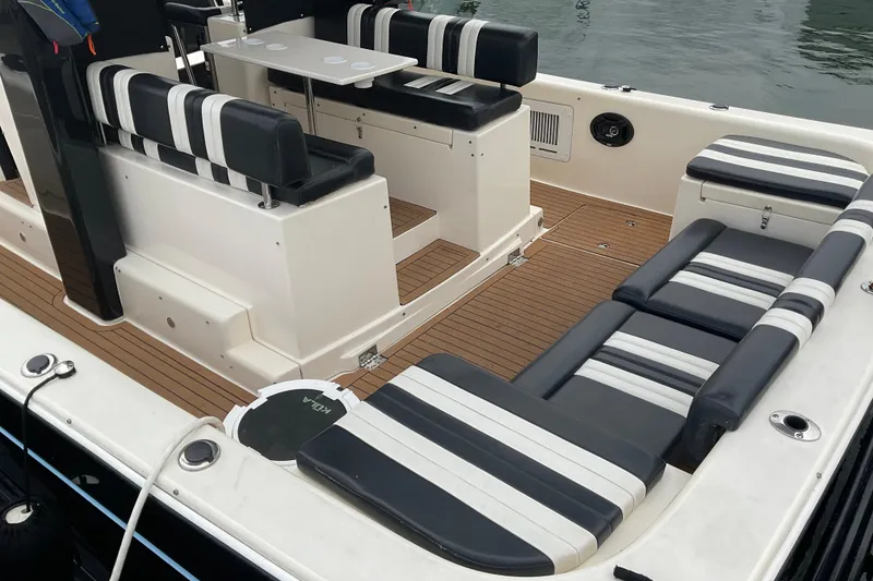 Slide: The Image of 2004 Rivolta PT Runner 4.0 boat interior with striped seating and wooden deck. - 17