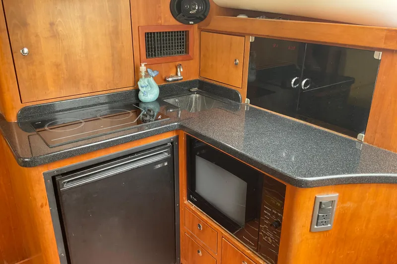 Slide: The Image of Compact kitchen area in a 2004 Rivolta PT Runner 4.0 boat with stove, sink, and fridge. - 20