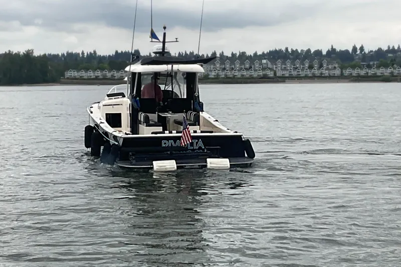 Slide: The Image of 2004 Rivolta PT Runner 4.0 boat on calm water with shoreline in background. - 4