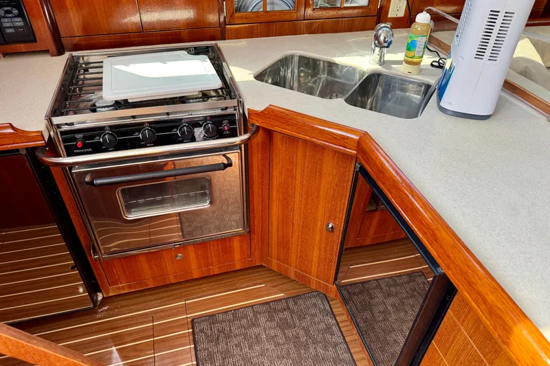 Slide: The Image of 2007 Hunter 41 Deck Salon kitchen with stove, dual sink, and wooden cabinetry. - 8