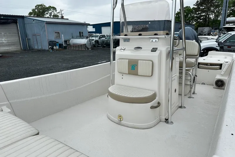 Slide: The Image of 2017 Carolina Skiff 238DLV boat interior with seating and console, parked outdoors. - 5