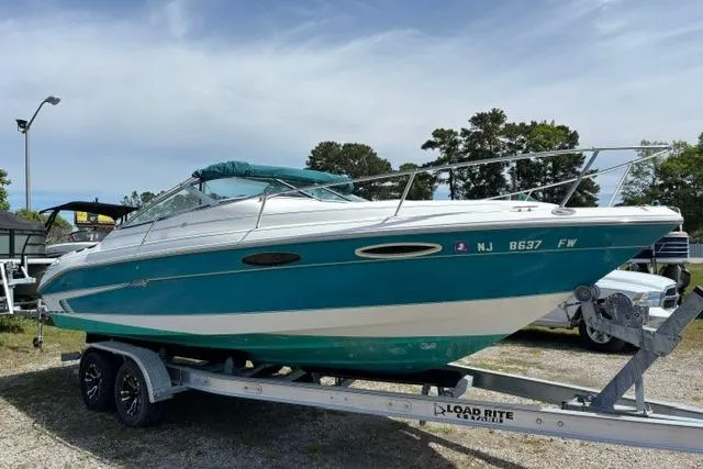 The Image of 1994 Sea Ray 240 boat on trailer, teal and white, parked outdoors. - 1