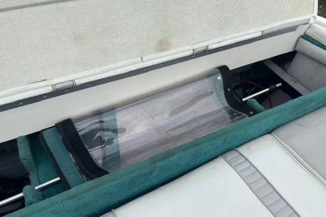 Slide: The Image of 1994 Sea Ray 240 boat interior storage compartment with teal accents and clear cover. - 22