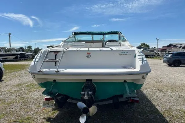 Slide: The Image of 1994 Sea Ray 240 boat with green accents, parked on gravel under a clear sky. - 4