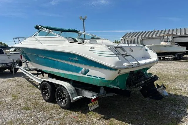 Slide: The Image of 1994 Sea Ray 240 boat on trailer, teal and white design, parked outdoors under clear sky. - 5