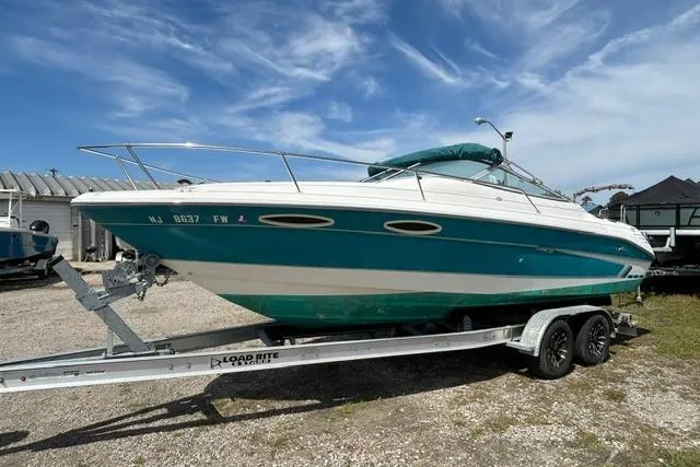 Slide: The Image of 1994 Sea Ray 240 boat on trailer under clear blue sky. - 7