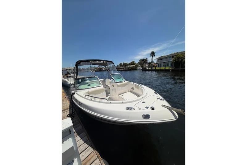 The Image of 2015 Robalo R227 Dual Console boat docked by a scenic waterfront. - 1