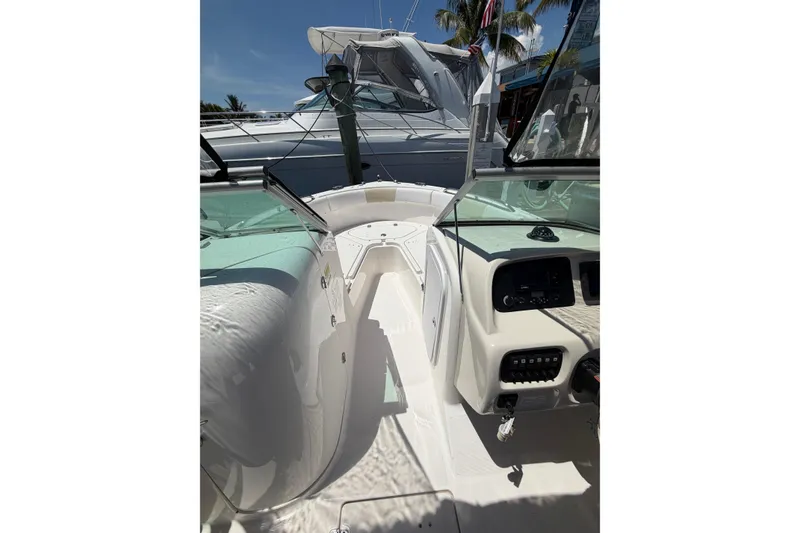 Slide: The Image of 2015 Robalo R227 Dual Console boat interior with dashboard and seating, docked under clear sky. - 18