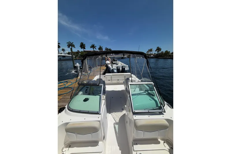 Slide: The Image of 2015 Robalo R227 Dual Console boat docked by palm trees under clear blue sky. - 21
