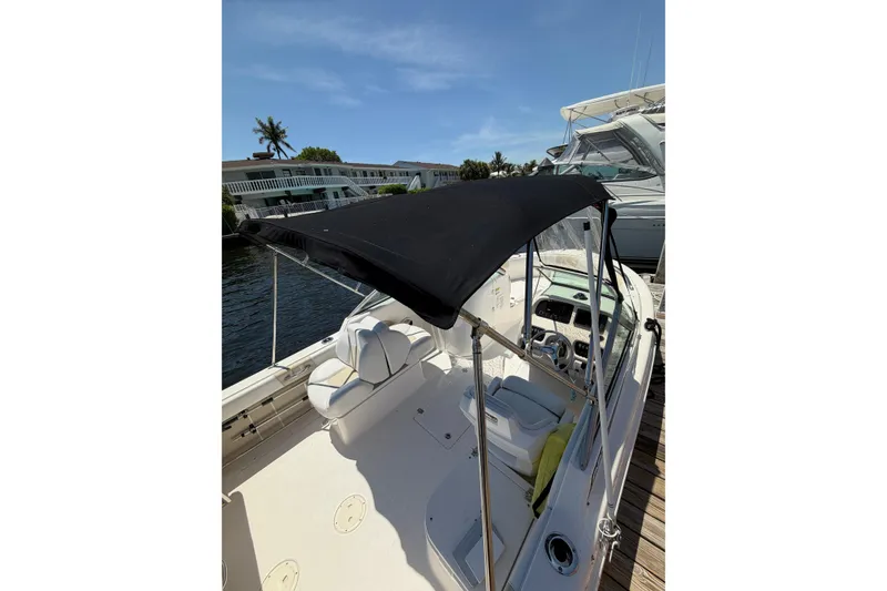 Slide: The Image of 2015 Robalo R227 Dual Console boat with black canopy docked by the water. - 24