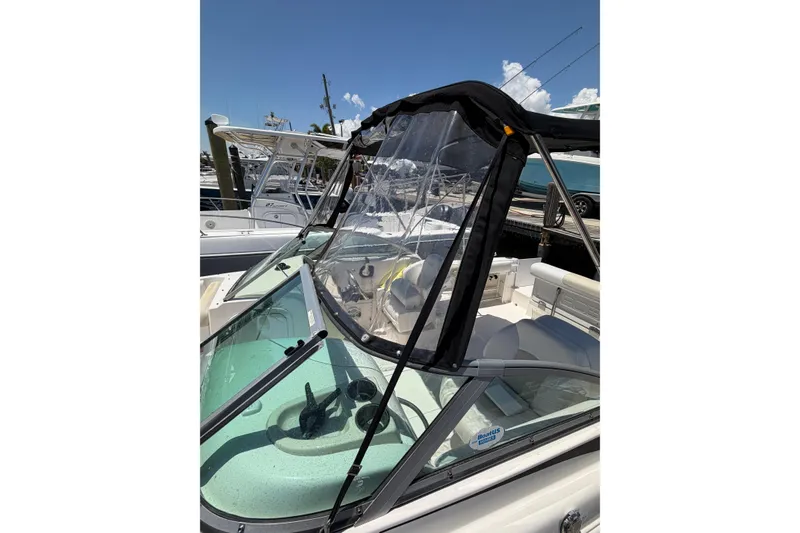 Slide: The Image of 2015 Robalo R227 Dual Console boat with clear canopy, docked under a sunny sky. - 32