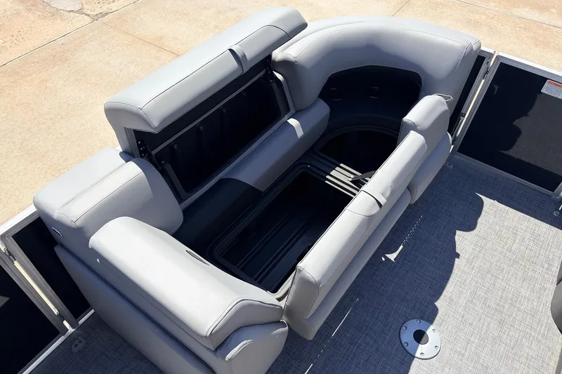 Slide: The Image of 2026 Sun Tracker Party Barge 22 DLX with open storage compartment and gray seating. - 17