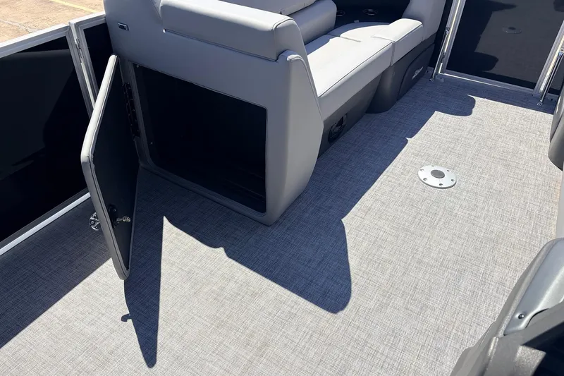 Slide: The Image of 2026 Sun Tracker Party Barge 22 DLX interior with open storage compartment and seating. - 19