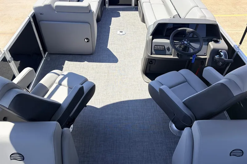 Slide: The Image of 2026 Sun Tracker Party Barge 22 DLX interior with gray seating and steering console. - 30