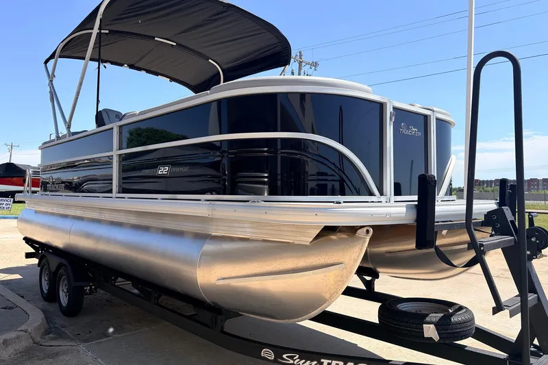 Slide: The Image of 2026 Sun Tracker Party Barge 22 DLX pontoon boat on trailer, featuring sleek design and canopy. - 4