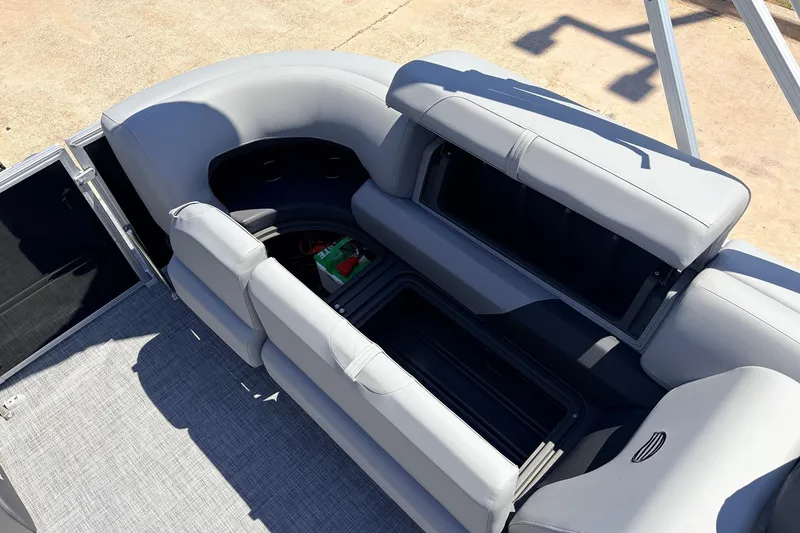 Slide: The Image of 2026 Sun Tracker Party Barge 22 DLX with open storage compartments and gray seating. - 42