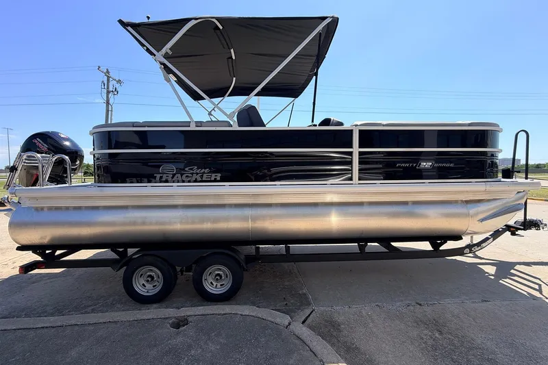 Slide: The Image of 2026 Sun Tracker Party Barge 22 DLX pontoon boat on trailer, featuring sleek design and canopy. - 5