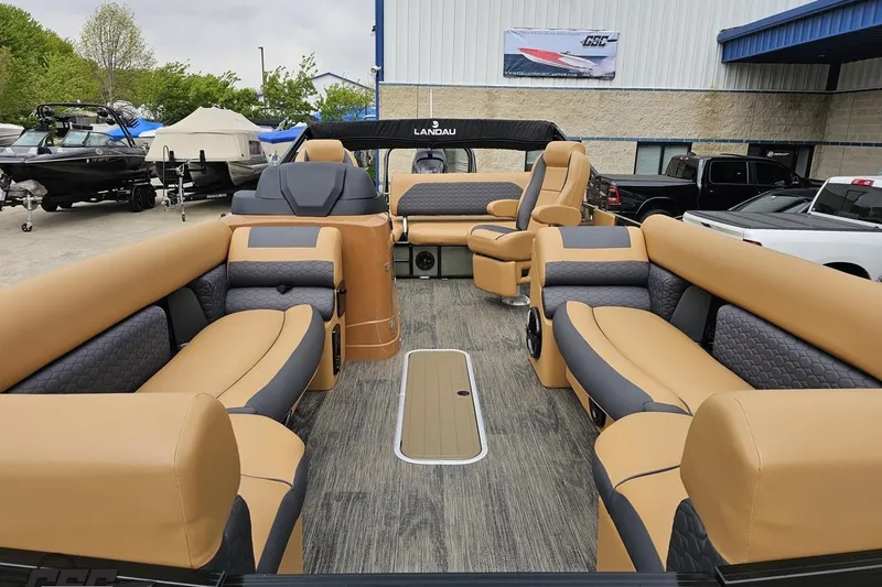 Slide: The Image of 2026 Landau Signature 25C pontoon boat with luxurious tan and gray seating, docked outdoors. - 17