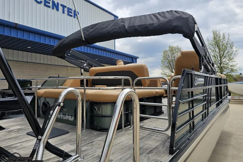 Slide: The Image of 2026 Landau Signature 25C pontoon boat with tan seating, docked near a blue building. - 35