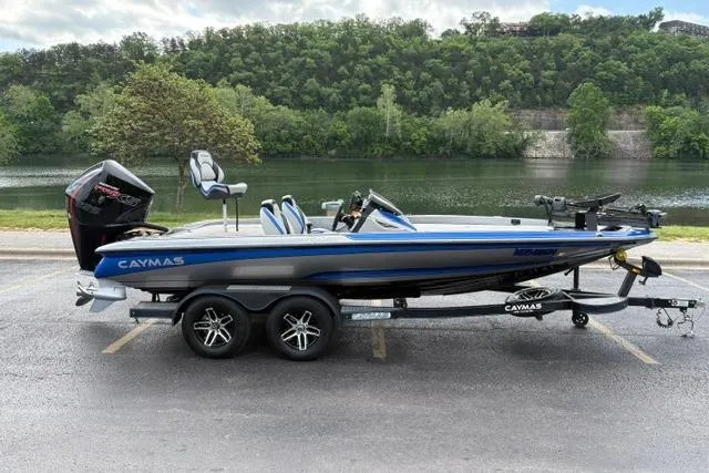 Slide: The Image of 2021 Caymas CX 19 boat on trailer by a scenic river backdrop. - 2