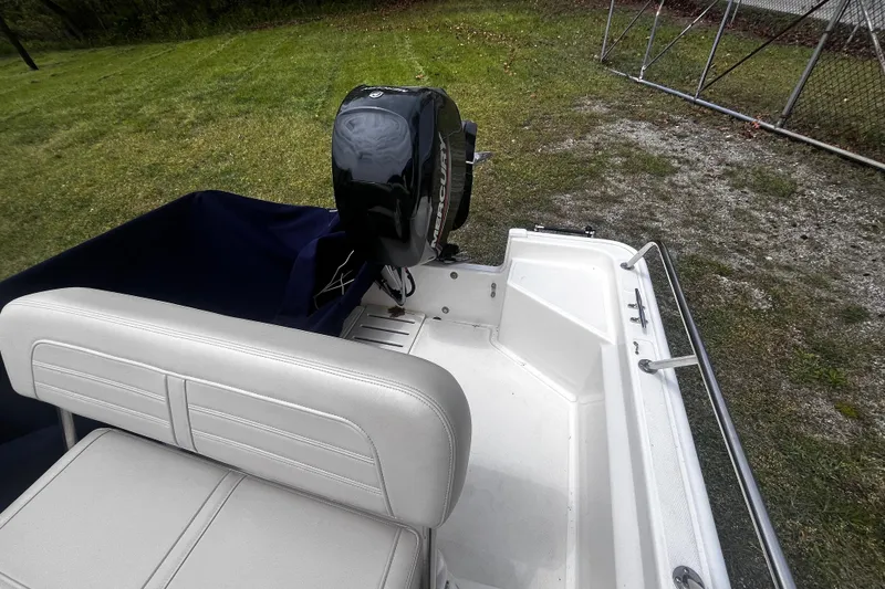 Slide: The Image of 2022 Boston Whaler 150 Montauk boat with outboard motor, parked on grass. - 11