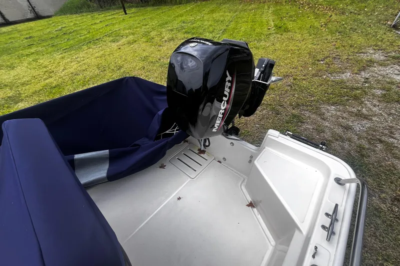 Slide: The Image of 2022 Boston Whaler 150 Montauk boat with Mercury outboard motor on grassy area. - 12