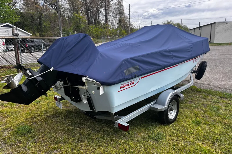 Slide: The Image of 2022 Boston Whaler 150 Montauk boat covered on trailer in outdoor setting. - 16