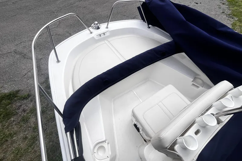 Slide: The Image of 2022 Boston Whaler 150 Montauk boat interior with seating and railing, covered in navy fabric. - 7