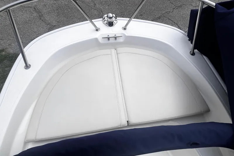 Slide: The Image of 2022 Boston Whaler 150 Montauk boat interior with cushioned seating and stainless steel railing. - 8