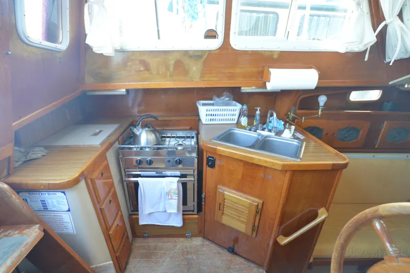 Slide: The Image of 1988 Gulf Pilot House kitchen with stove, sink, and wooden cabinetry in a cozy boat interior. - 5