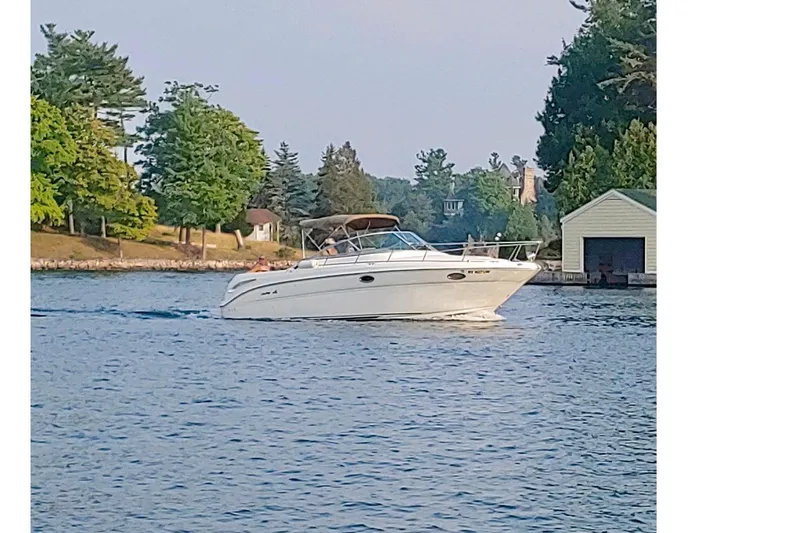 Slide: The Image of 2000 Sea Ray 290 Amberjack cruising on a serene lake near a wooded shoreline. - 1