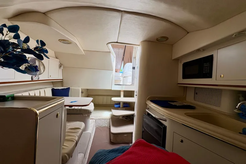Slide: The Image of Interior of 2000 Sea Ray 290 Amberjack boat, featuring kitchenette and seating area. - 16