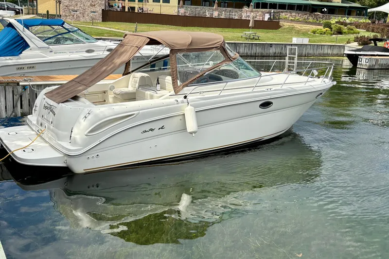 Slide: The Image of 2000 Sea Ray 290 Amberjack boat docked in a marina, featuring a beige canopy. - 5
