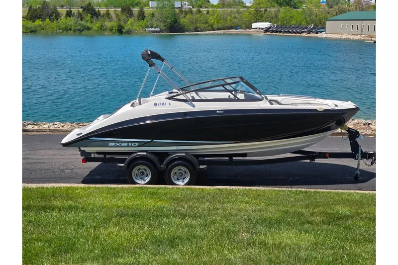 The Image of 2019 Yamaha Boats SX210 on trailer by a scenic lake. - 0