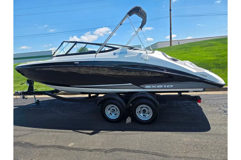 Slide: The Image of 2019 Yamaha Boats SX210 on trailer, sleek black and white design, sunny day background. - 4