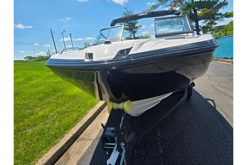 Slide: The Image of 2019 Yamaha Boats SX210 on trailer, parked near a grassy area and water. - 6