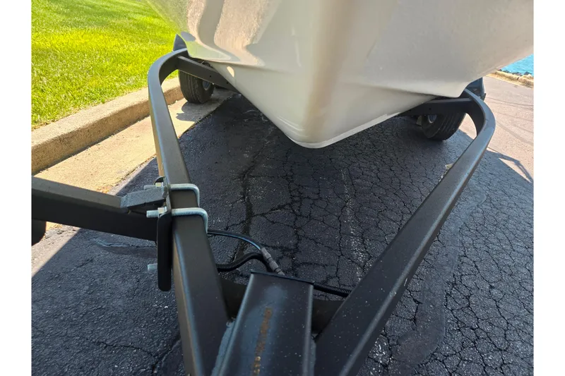 Slide: The Image of 2019 Yamaha Boats SX210 on trailer, parked on cracked asphalt near grass. - 7
