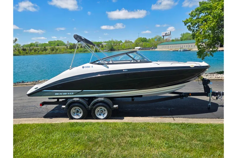 Slide: The Image of 2019 Yamaha Boats SX210 on trailer by a scenic waterfront. - 9