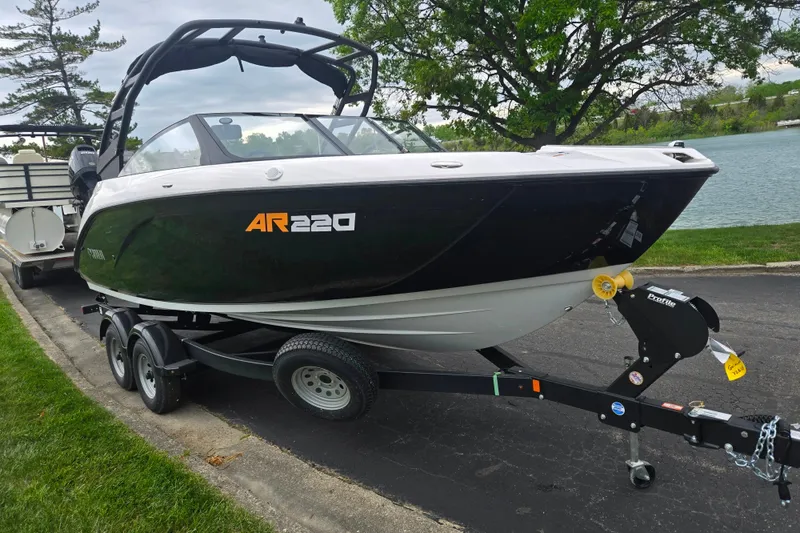 Slide: The Image of 2024 Yamaha Boats AR220 on trailer by a lakeside, showcasing sleek design and modern features. - 8