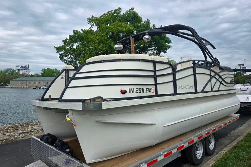 Slide: The Image of 2022 Lexington 621TT Extreme pontoon boat on trailer by a lakeside. - 7