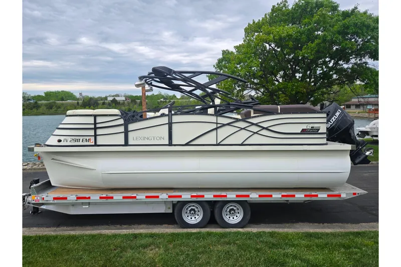 Slide: The Image of 2022 Lexington 621TT Extreme pontoon boat on trailer by a lake. - 8