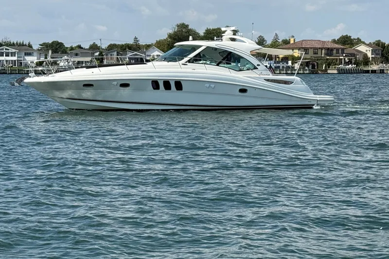 Slide: The Image of 2007 Sea Ray 48 Sundancer yacht cruising on a calm waterway near residential area. - 4