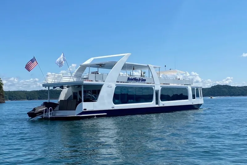 The Image of Modern 2020 Thoroughbred 20 x 102 houseboat on a serene lake under clear skies. - 1