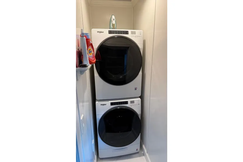 Slide: The Image of Stacked Whirlpool washer and dryer in a compact laundry space with detergent on the shelf. - 32